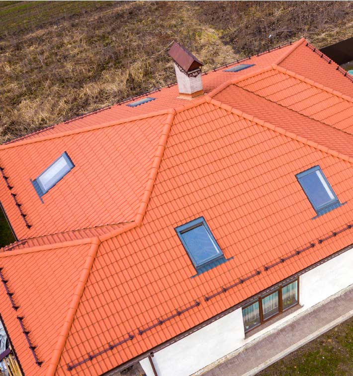 Close-up of a vibrant terracotta tile roof system installation in Vacaville, showcasing expert craftsmanship and skylight integration by Capital Roofcare for a long-term sustainable home exterior.