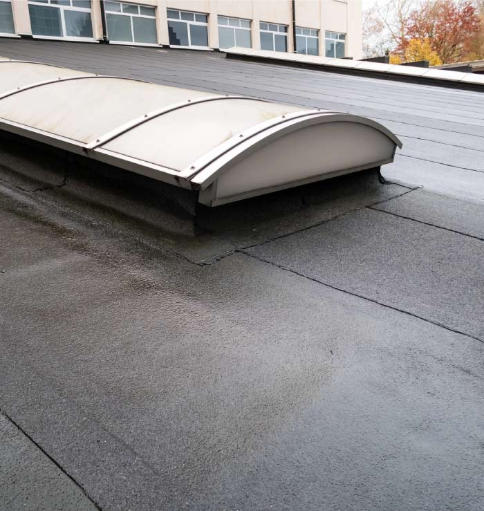 Modern commercial low-slope roof repair in Vacaville featuring waterproofed arched skylights and smooth-surface bitumen membrane for superior drainage.