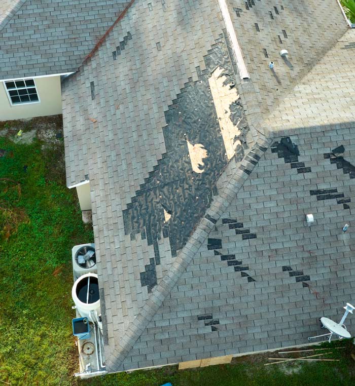 Aerial view of a damaged composition shingle roof in Sacramento showing missing shingles and exposed underlayment in need of immediate roof leak repairs.