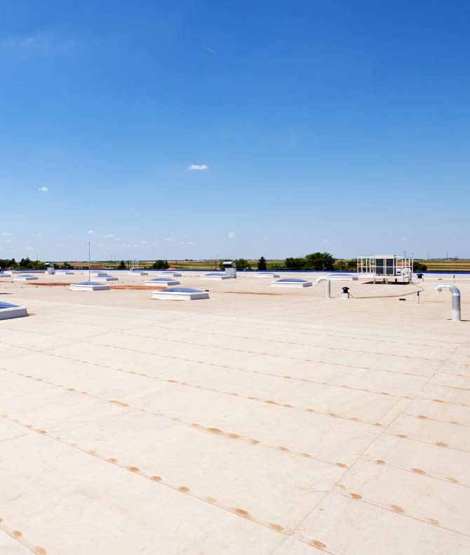 Expansive white TPO cool roof system installed on a commercial building featuring multiple skylights and ventilation units for energy efficiency.