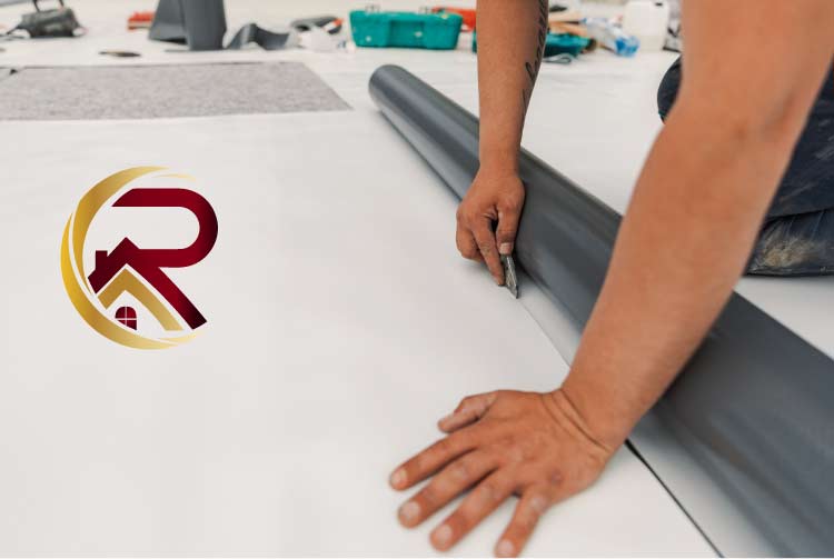 Close-up of a roofer's hands using a utility knife to precisely cut a roll of grey TPO roofing membrane over a white base layer during a commercial flat roof installation, with a red and gold company logo.