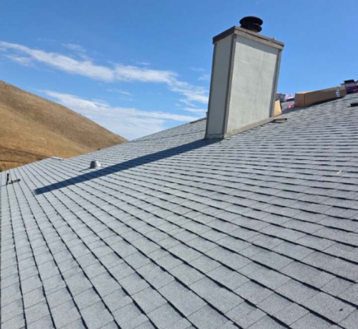 Clean architectural perspective of a light grey shingle roof and chimney, demonstrating the uniform layout of high-quality roofing materials.