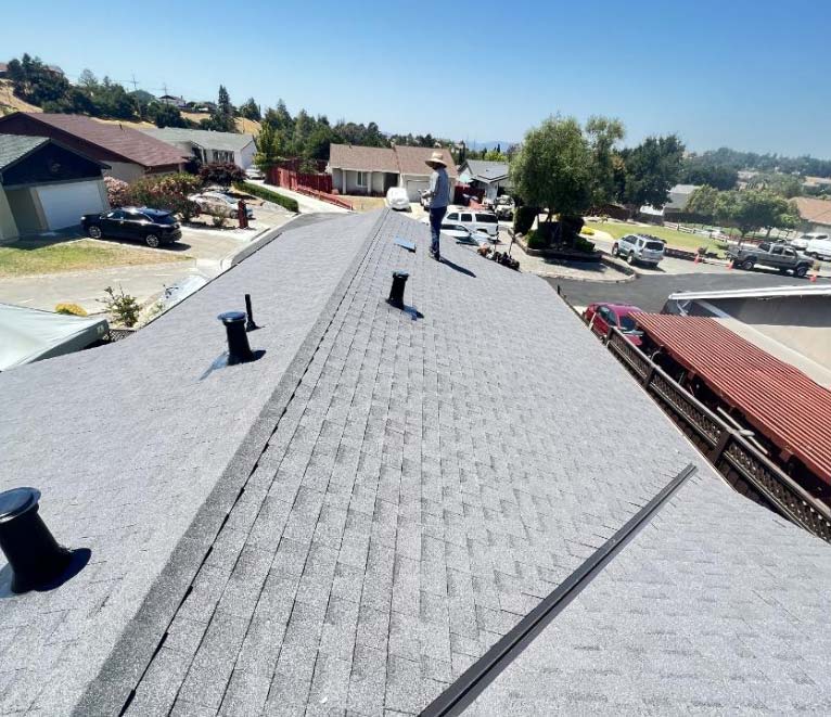 Close-up of a professionally installed asphalt shingle roof in Vacaville featuring multiple attic ventilation components and a clean ridge line.