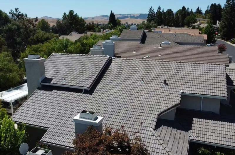 Aerial view of a large residential property featuring a complex multi-level tile roofing system in a neutral earthy tone.